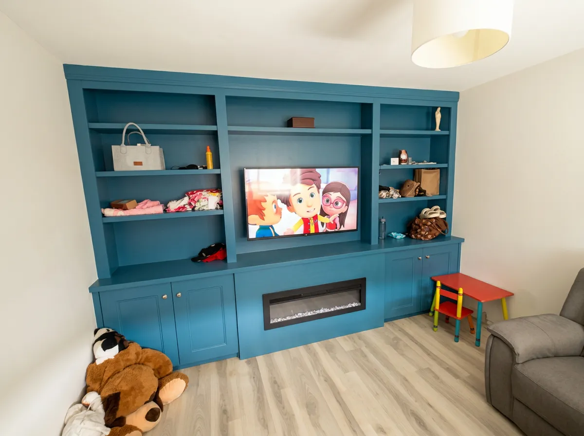 Bright teal media wall with open shelving and inset fire in a family room, with a small children's table and chair