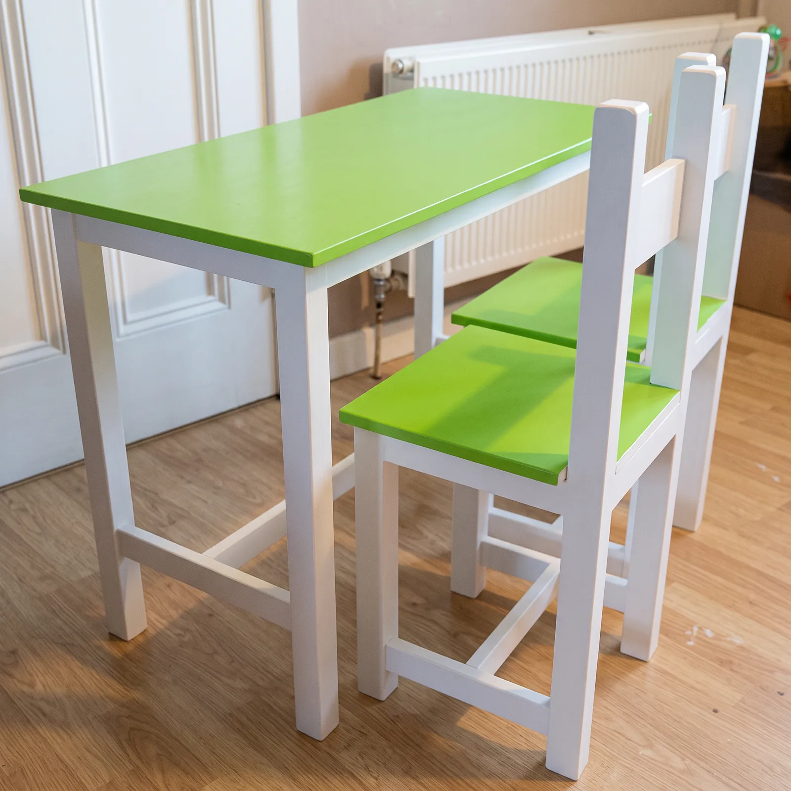 Children's table and chairs with white frames and bright green top and seats